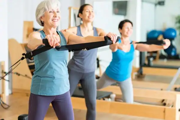 Toning Arms After 60: Empowering Womens Fitness Through Effective Weight Training 2 older woman doing weight training Feltham and resistance in the gym to tone upper arms