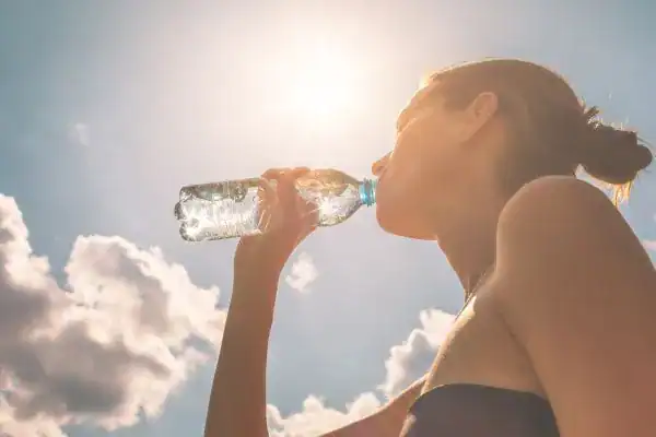 Hydration: The Secret Ingredient for a Toned Stomach and Enhanced Fitness 3 Image of woman drinking water to hydrate Feltham after run.