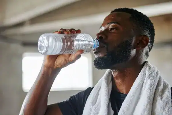 Hydration: The Secret Ingredient for a Toned Stomach and Enhanced Fitness 1 Image of man drinking water to improve hydration Feltham after work out.
